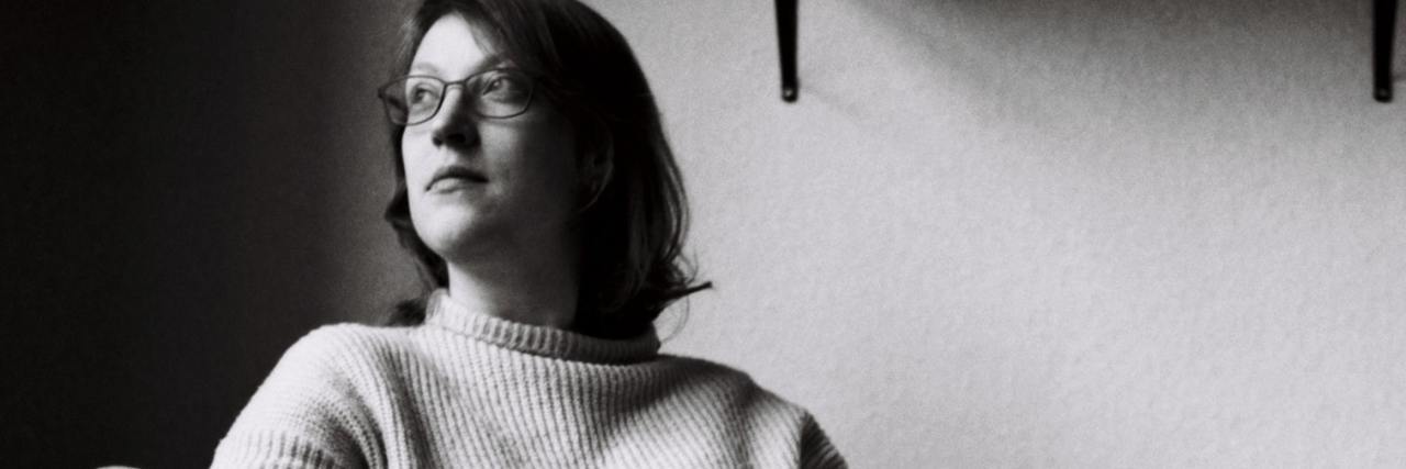 How Attachment-Focused EMDR Therapy Is Different and How It Works black and white photo of a woman on a chair, looking out of a window, thinking to herself with a book in her lap