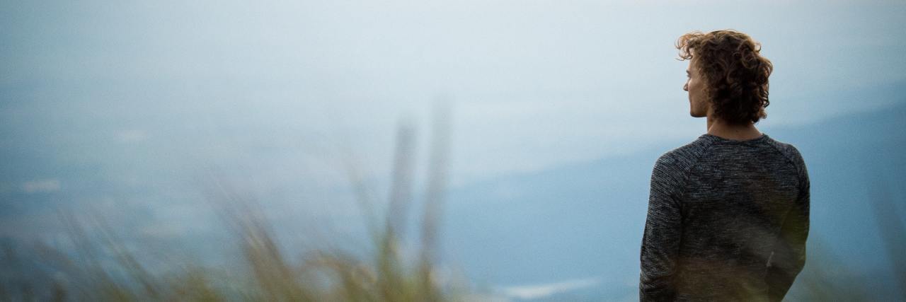 What Harm Reduction Means and Why It Could Help Reduce Drug Addiction photo of a man on a hilltop overlooking field at sunset or sunrise
