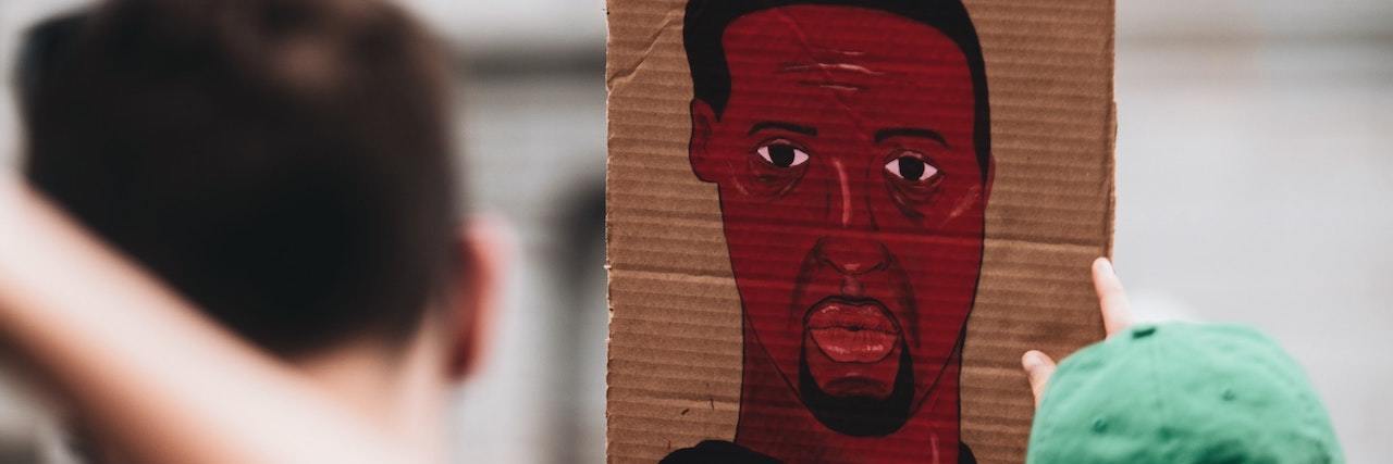 A sign with a paining of George Floyd at a Black Lives Matter protest.