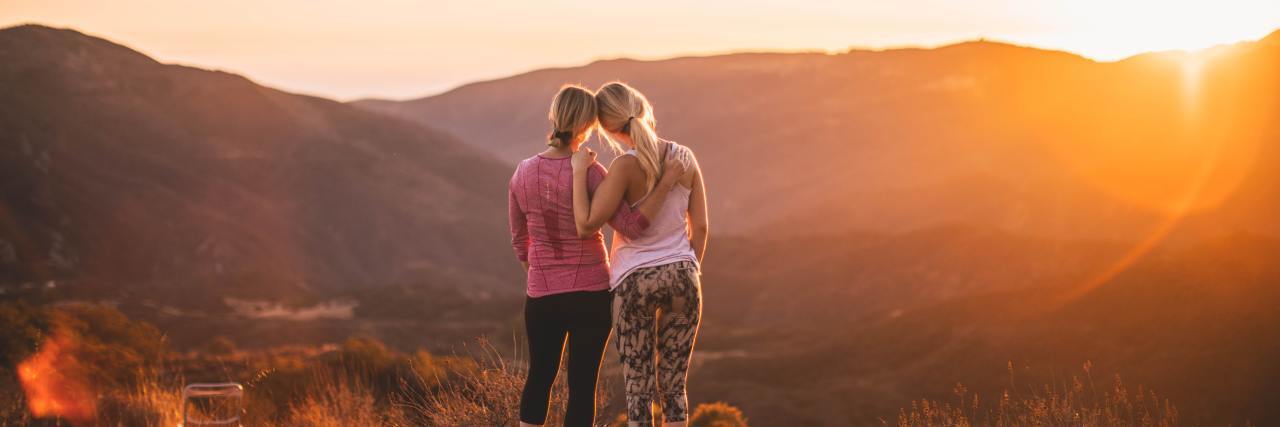 How To Make Trauma Survivors Feel Seen and Understood photo of two women embracing on hills while watching sunset