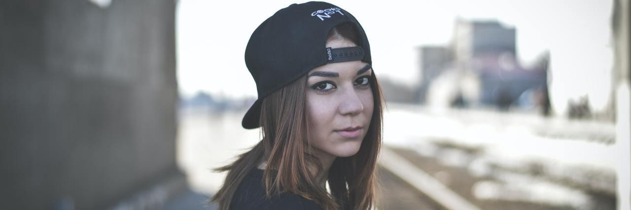 My Mental Illness Doesn't Make Me a 'Bad' Person A young white girl turning around, wearing a hat on backwards