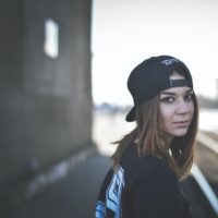 A young white girl turning around, wearing a hat on backwards