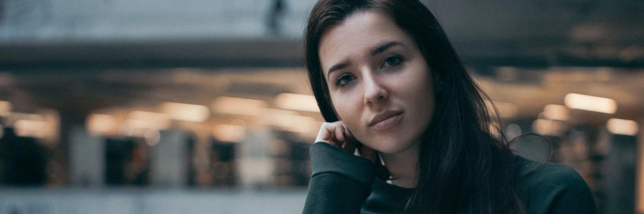 What High-Functioning Bipolar Disorder Looks Like photo of a woman leaning on a wall, looking into the camera with a sad expression