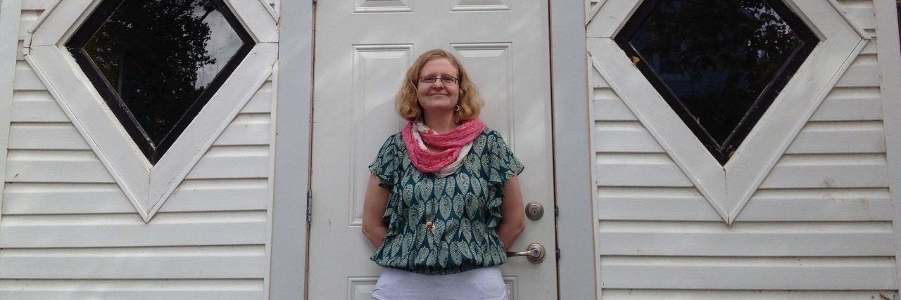 What It Really Feels Like To Be 'Triggered' by Trauma photo of the contributor standing in front of a white wooden building