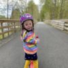 Lily wearing a rainbow striped shirt and purple helmet.