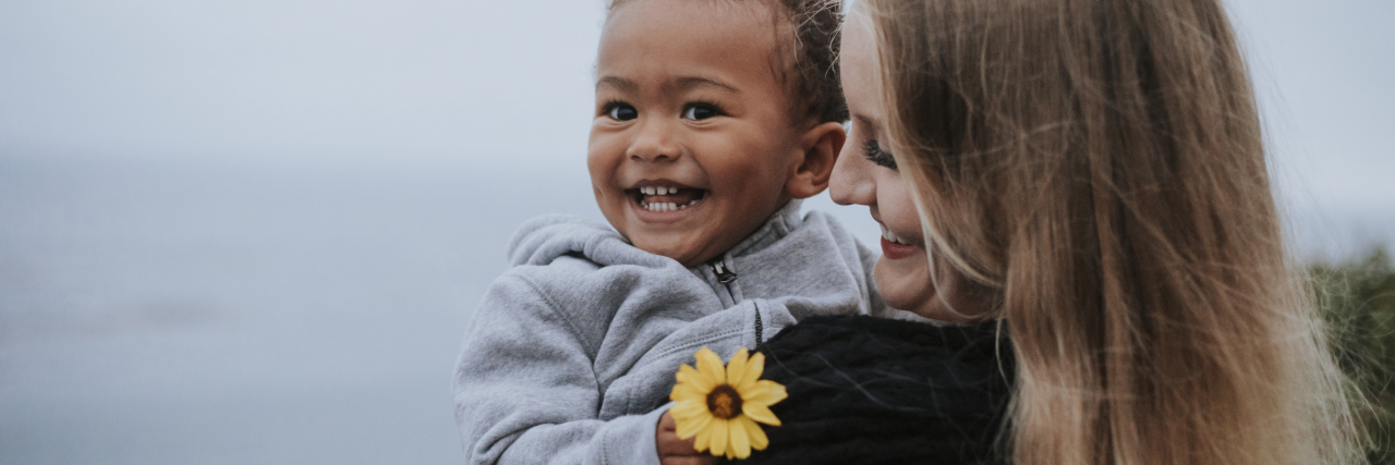 Advice for Parents of Children With HIE, From an Adult With HIE Young boy holding a flower carried by his mom.