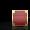 A closed jack-in-the-box that's red with gold trimmings on a black background