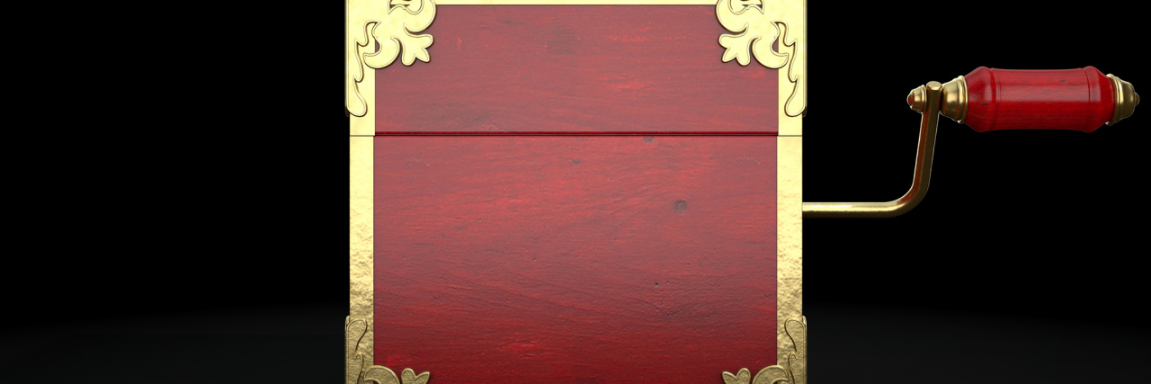 How Trauma Is Like a Jack-in-the-Box A closed jack-in-the-box that's red with gold trimmings on a black background