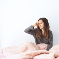 Woman in bed with her hand on her head