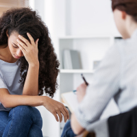 Therapist talking to young Black woman.