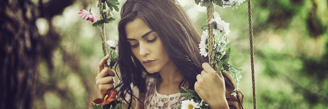 The Good and Bad in 10 of My Borderline Personality Disorder Symptoms A young woman sitting on a swing in the forest looking down
