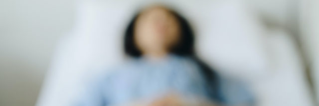 Blurred image of woman lying in hospital bed
