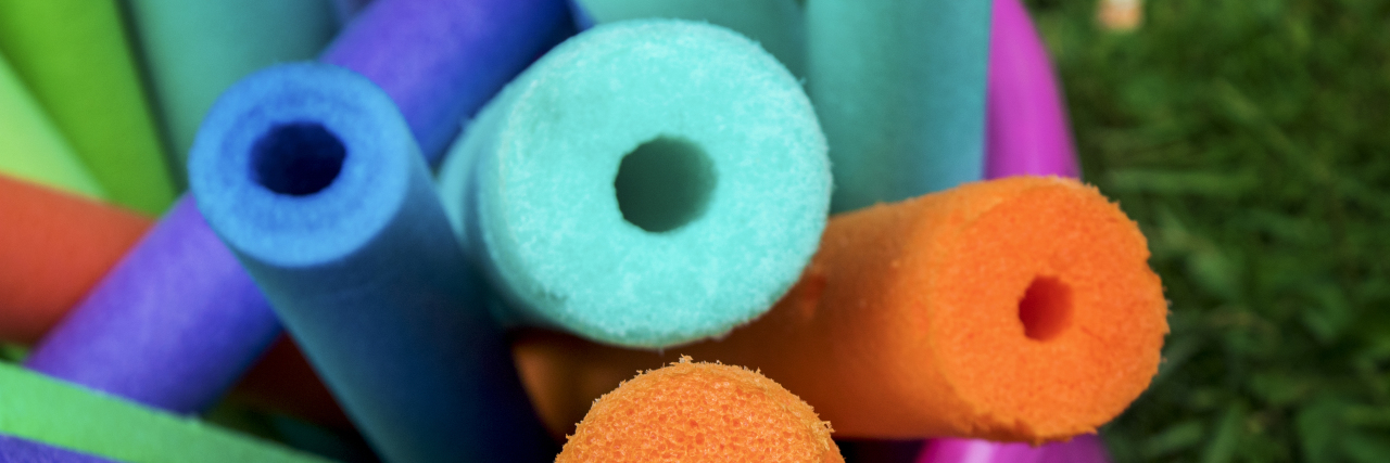 Learning to Accept and Embrace Adaptive Equipment for My Disability Bucket full of foam pool noodles.