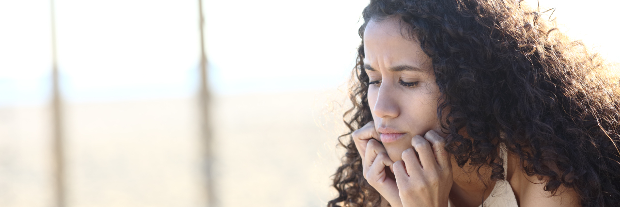 How to Support Your Teen's Mental Health This Post-Pandemic Summer Teen girl looking down sitting on the beach.