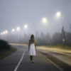 woman in white dress walking alone on a dark street
