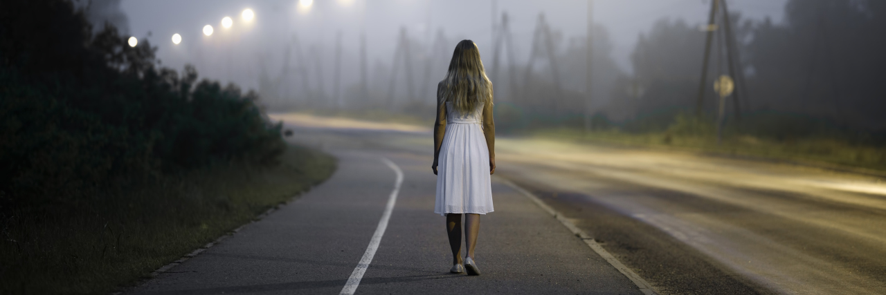 woman in white dress walking alone on a dark street