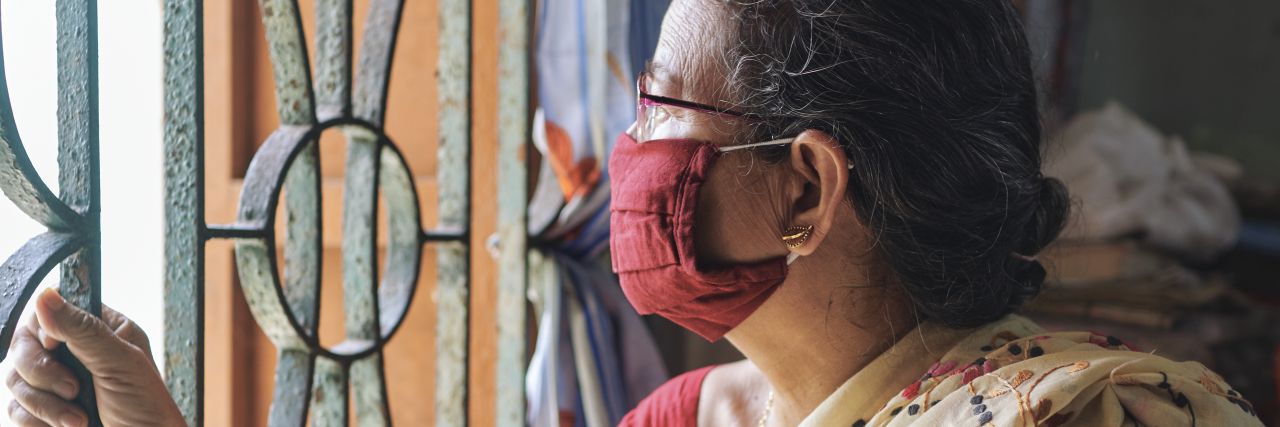 Indian woman looking outside with a mask on