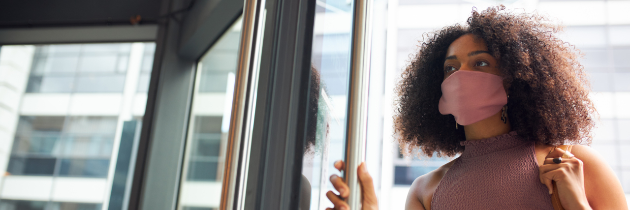 The Anxiety Associated With Navigating a Post Mask Mandate World Woman standing in a doorway with a mask on