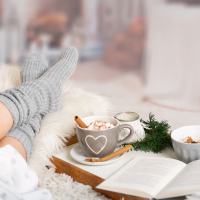 woman on sofa with a book and hot chocolate.