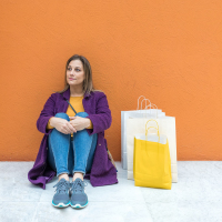 Woman sitting on floor with shopping bags.