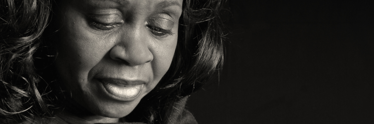 Worrying About My Daughter Triggered My Sexual Trauma black and white photo of a woman looking sad or thoughtful, head lowered