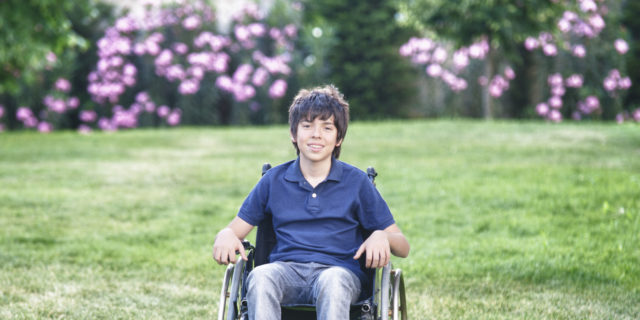 Young boy in a wheelchair outdoors.
