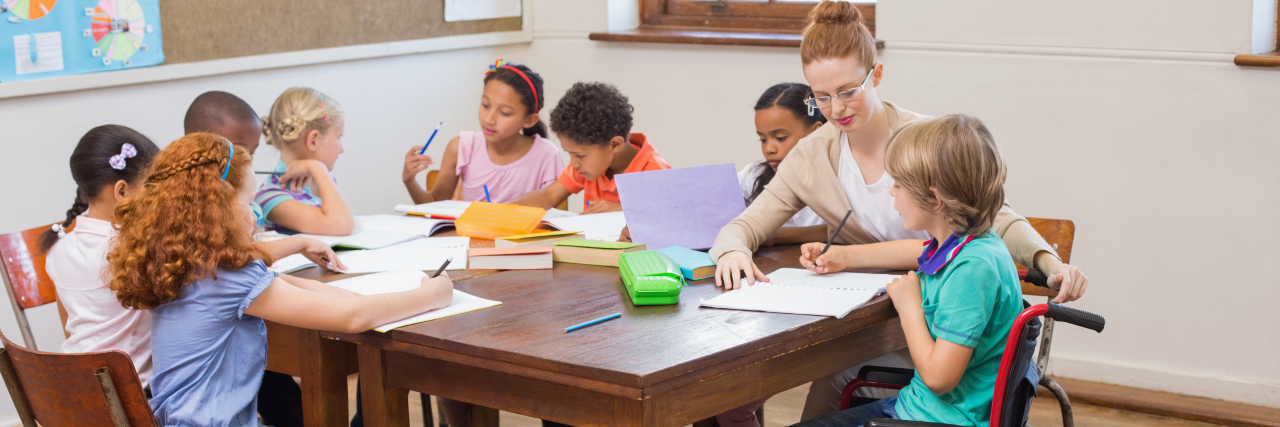 Why We Need More Disabled Educators Teacher helping pupils in classroom.