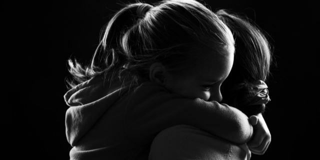 black and white image of a mom and young daughter hugging