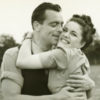 Young couple embracing in field, black and white photo.