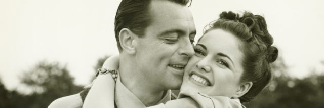 Young couple embracing in field, black and white photo.