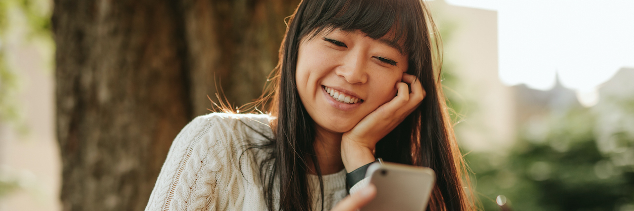 Letting Work Become My Identity Led to My Stay in the Psychiatric Ward AAPI woman sitting outside smiling with a cup of coffee