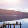 a woman sitting alone by a lake