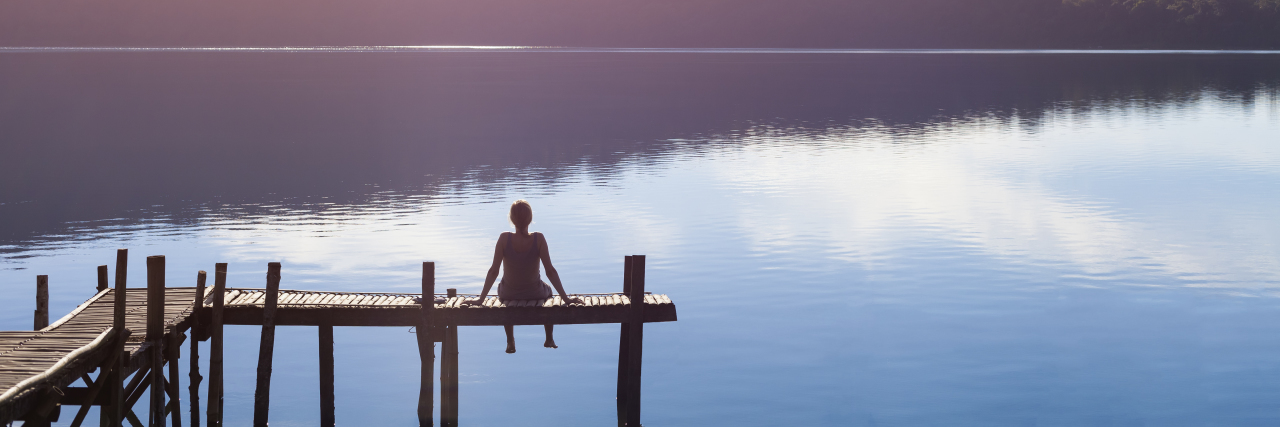 a woman sitting alone by a lake
