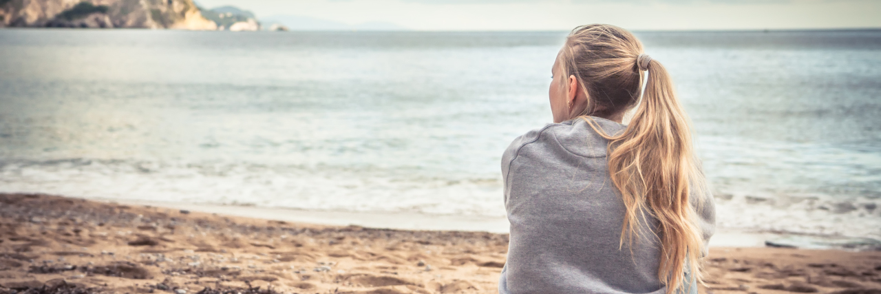 How Mindfulness Based Stress Reduction Is a Game Changer a woman sitting on the beach looking at the view