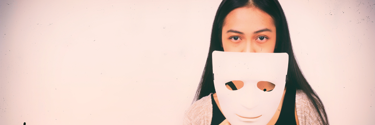 Trying to 'Pass' as Neurotypical as Someone on the Autism Spectrum Woman holding theatre mask near her face.