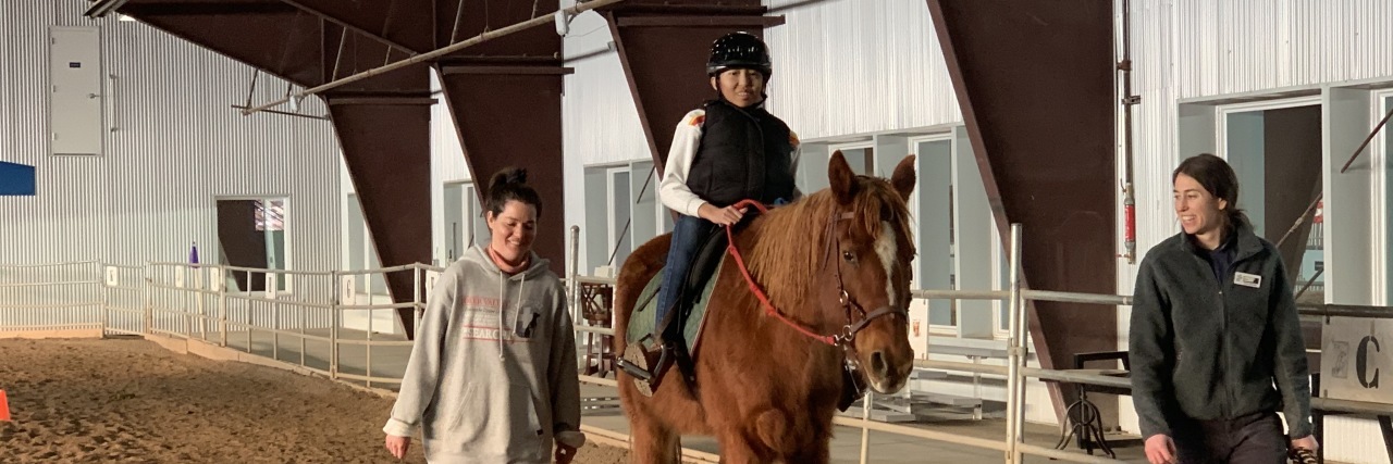 My Daughter's Path From Orphanage to Multi-Sport Disability Athlete Ping Ping riding a horse.