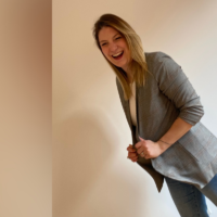 Photo of author: A young white woman in a blazer posing and laughing