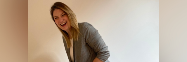 Photo of author: A young white woman in a blazer posing and laughing
