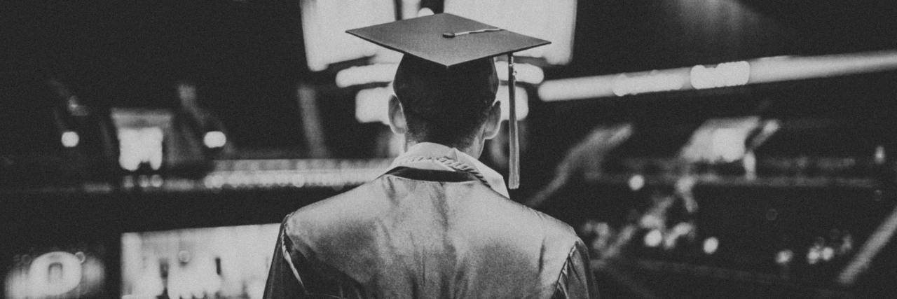 black and white photo taken from behind of a young man with a mortar board, graduation