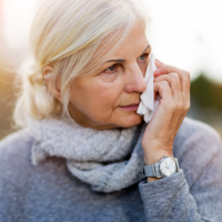 Photo of a mature woman holding a tissue to her face