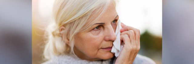 Photo of a mature woman holding a tissue to her face