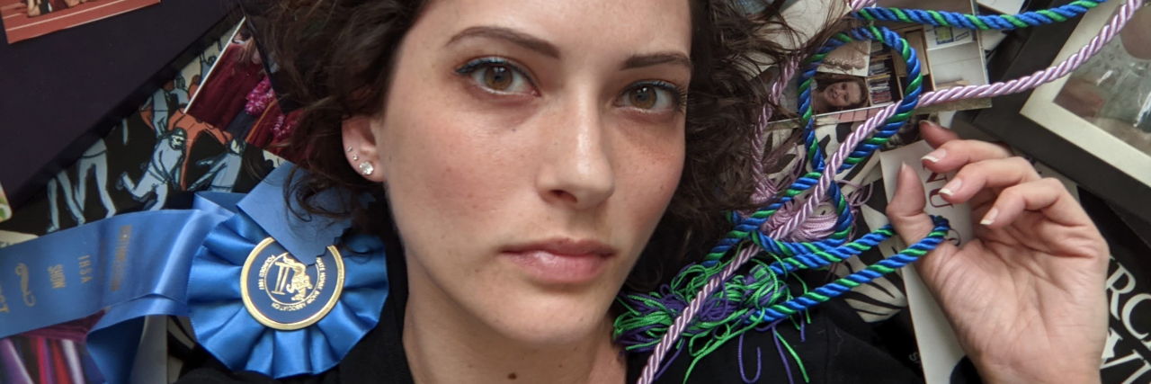 When You Feel Like Mental Illness Stole Your Identity photo of the contributor lying on a collection of photos and other memories, looking into the camera