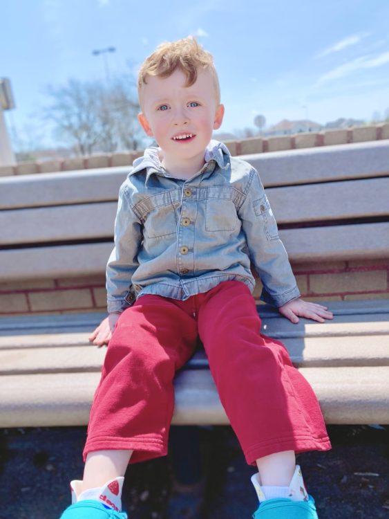 Jacquelyn's son sitting on a park bench..