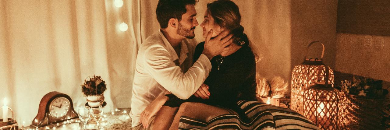 Read This If You're Worried About Intimacy After Sexual Assault photo of a couple in bed surrounded by candles, intimate