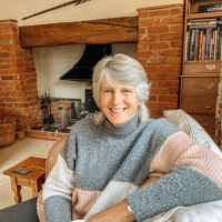 Kerry sitting in front of an old brick fireplace.