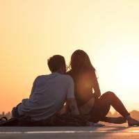 photo of a man and woman sitting together at sunset