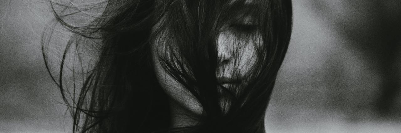 black and white photo of a young woman with her eyes closed, hair covering her face
