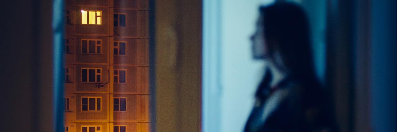 Experiencing Paranoid Ideation With Borderline Personality Disorder blurred photo of a woman looking out of apartment window at night