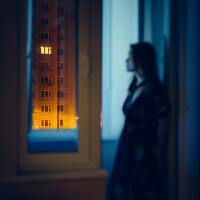 blurred photo of a woman looking out of apartment window at night