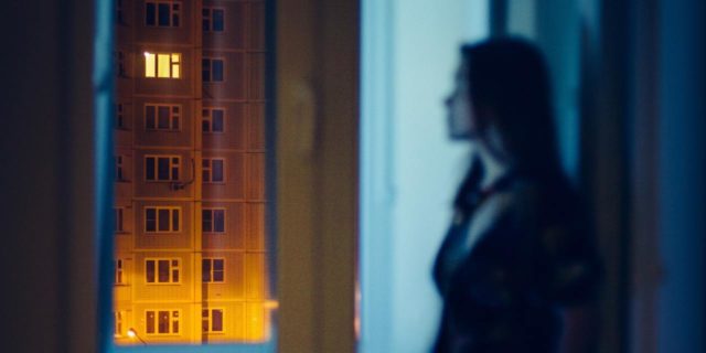 blurred photo of a woman looking out of apartment window at night